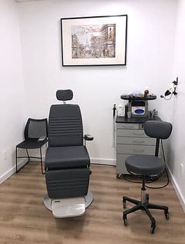 A second examination room with an ENT treatment chair, a physician's stool and an instrument cart